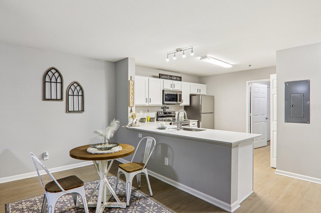 A kitchen with a table and chairs in front of a sink.