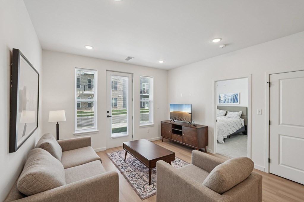 A living room with a brown couch, a coffee table, and a television.