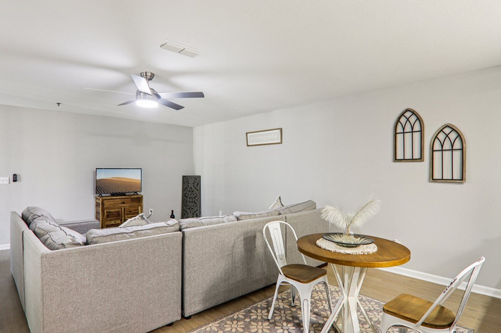 A living room with a grey couch, a wooden coffee table, and a ceiling fan.