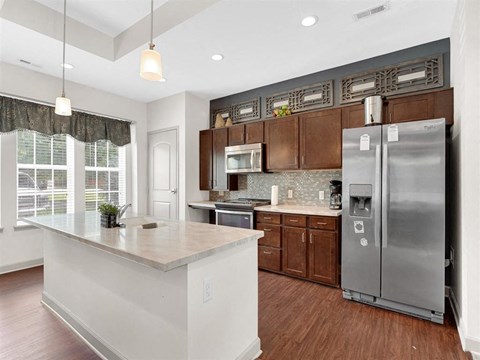 A kitchen with a white island and a stainless steel refrigerator.