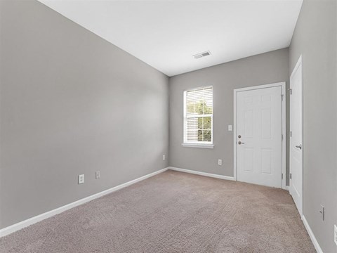 A room with a carpeted floor and a window with blinds.