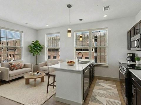A modern kitchen with a large island, a dining table with chairs, and a view of the city.