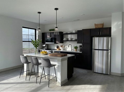 A modern kitchen with a large island and grey chairs.