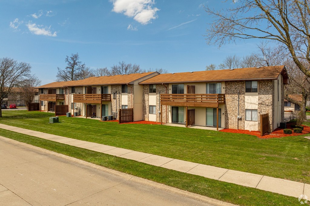 Apartment building with a sidewalk and green grass.