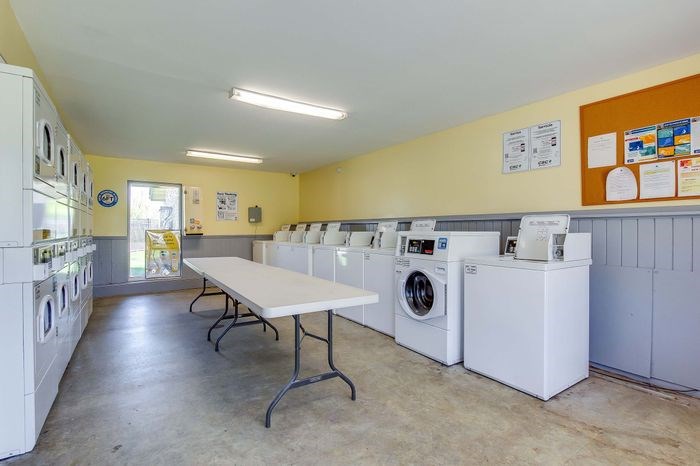 A laundromat with a long white table and several washing machines.