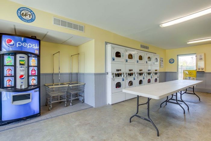 A Pepsi vending machine sits next to a table in a room.