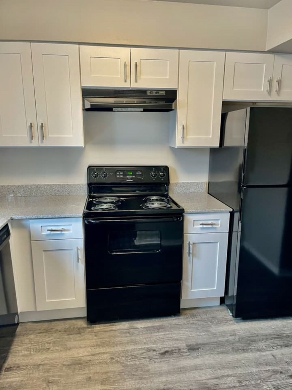 A black stove and oven in a kitchen with white cabinets.