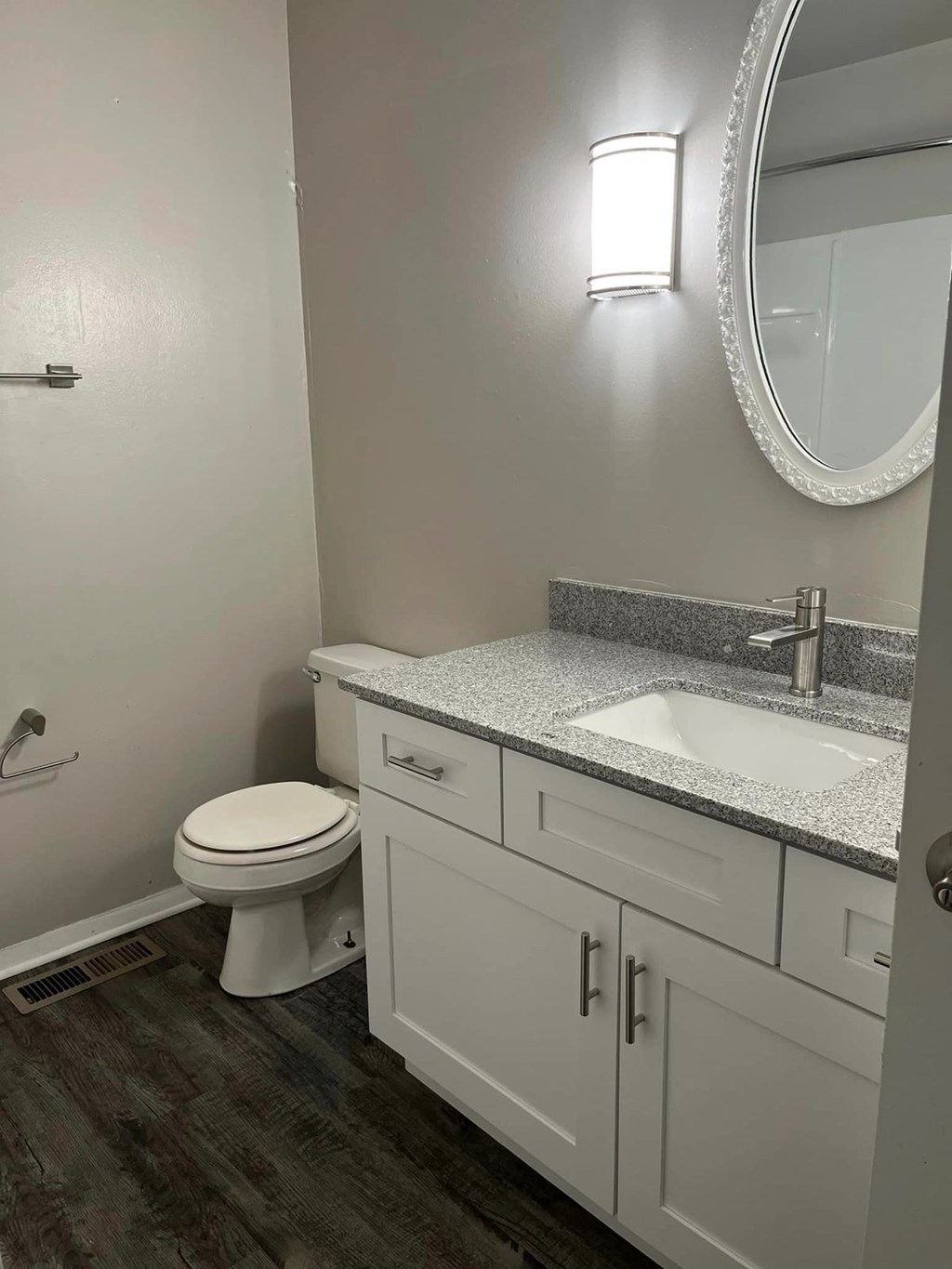 A bathroom with a toilet, sink, and mirror.