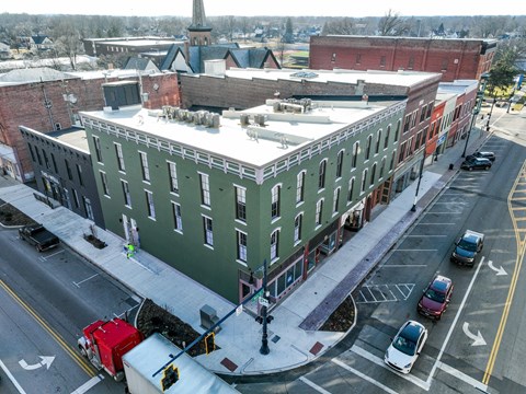 A green building with a parking lot in front of it.