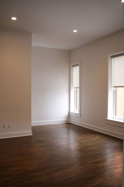 A room with wooden floors and two windows.