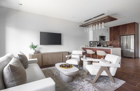 A modern living room with a white sofa, a wooden coffee table, and a TV mounted on the wall.