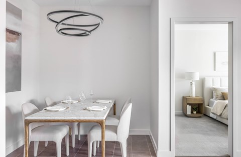 A modern dining room with a white table and chairs.
