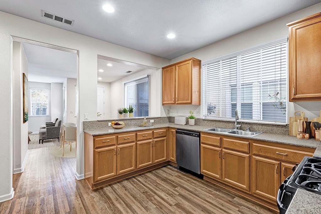 A kitchen with wooden cabinets and a black dishwasher.