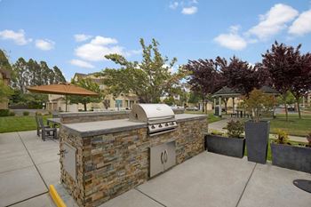 A stone outdoor kitchen with a grill and seating area.