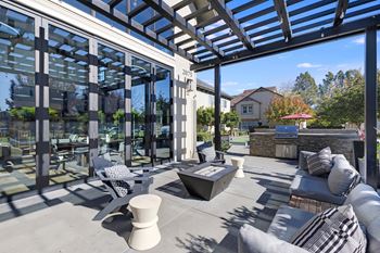 A modern outdoor patio with a glass wall and a stone fireplace.