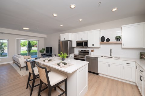 A modern kitchen with white cabinets and a dining table.