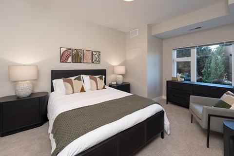 A bedroom with a large bed and a chair.
