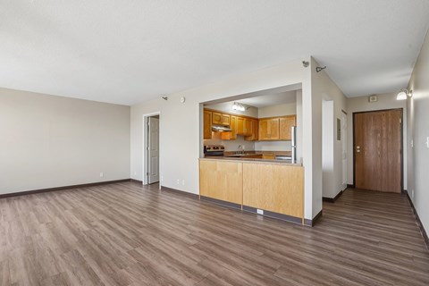 A kitchen with wooden cabinets and a countertop is visible through a doorway.