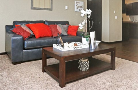 A living room with a black leather couch and a wooden coffee table.
