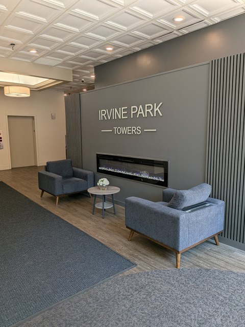A room with a fireplace and chairs with Irvine Park Towers written on the wall.