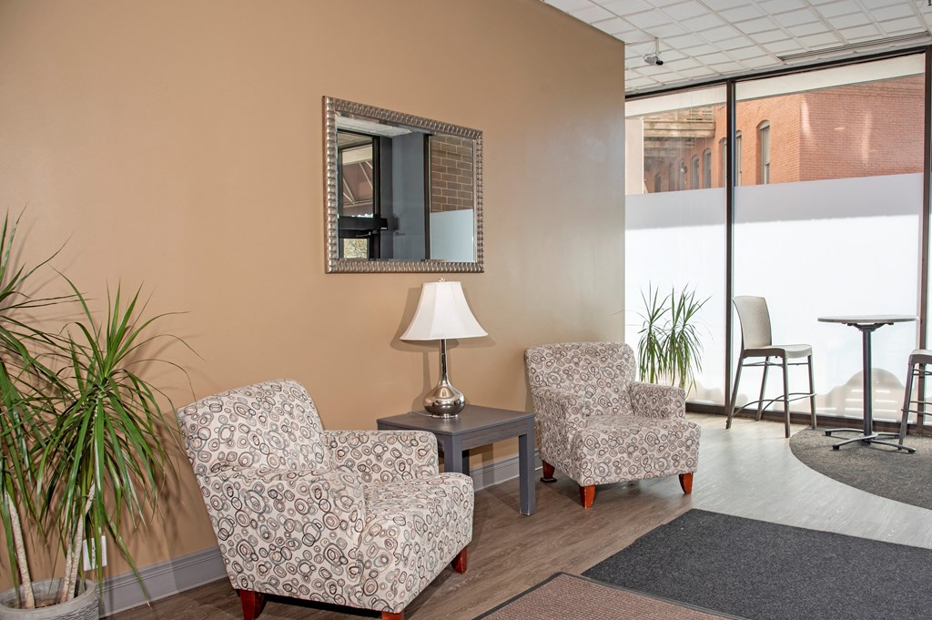 a living room with two chairs and a mirror on the wall