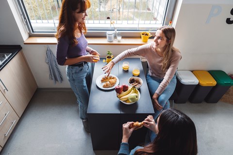 Three women are having a meal together in a kitchen.