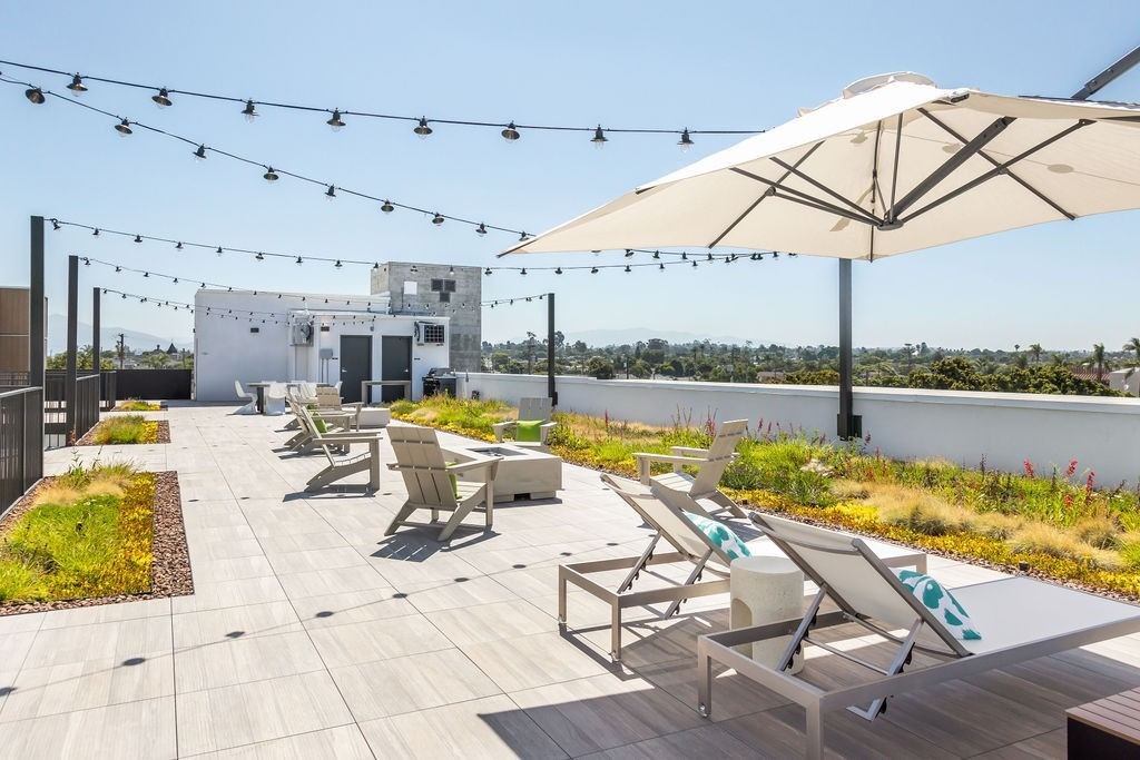 A patio with chairs and umbrellas is set on a rooftop.