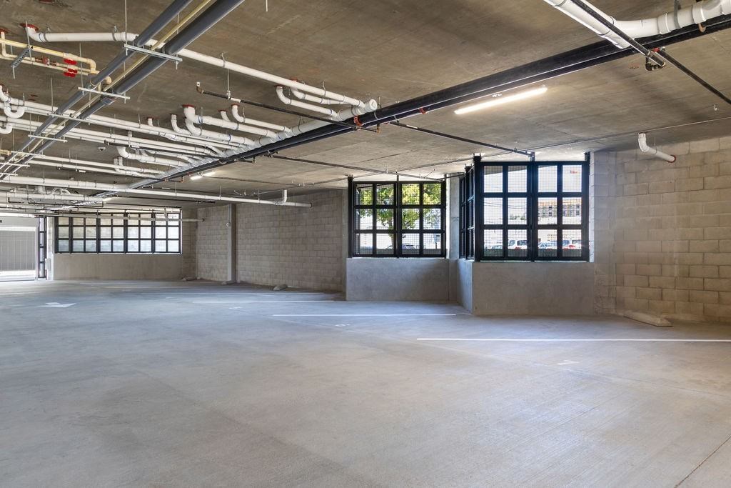 A large, empty industrial space with concrete floors and exposed ceiling pipes.