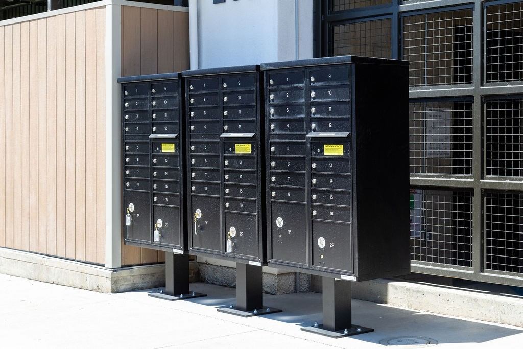 Three black mailboxes are lined up on a sidewalk.