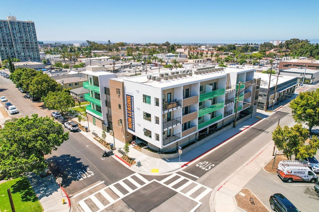 A modern building with the word "SUNSET" on the side is surrounded by trees and a busy street.