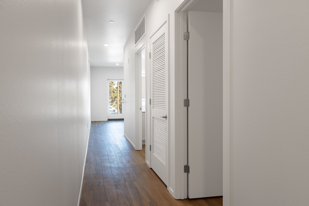 A long hallway with white walls and wood floors.