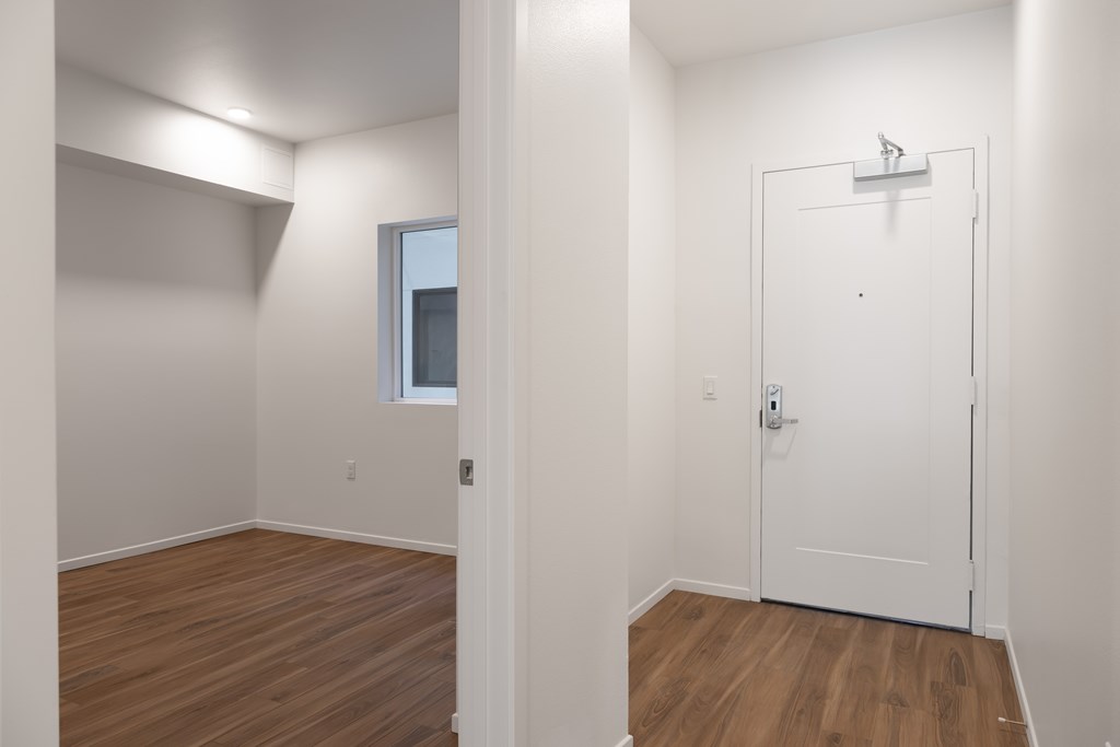 A white door with a silver handle is in a room with wooden floors.