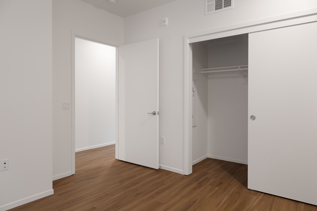 A white room with a wooden floor and two open doors.