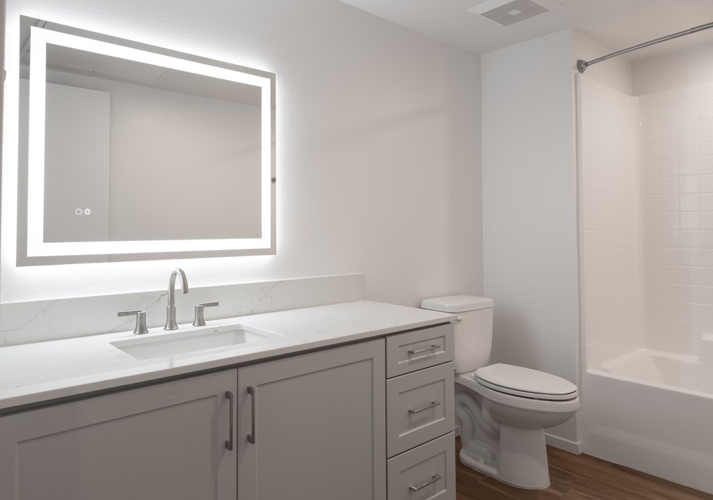 A white bathroom with a sink, toilet, and mirror.