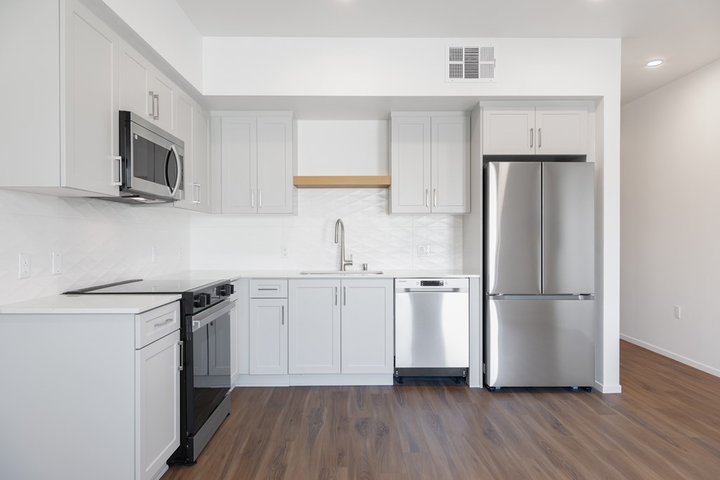 A kitchen with white cabinets and a stainless steel refrigerator.