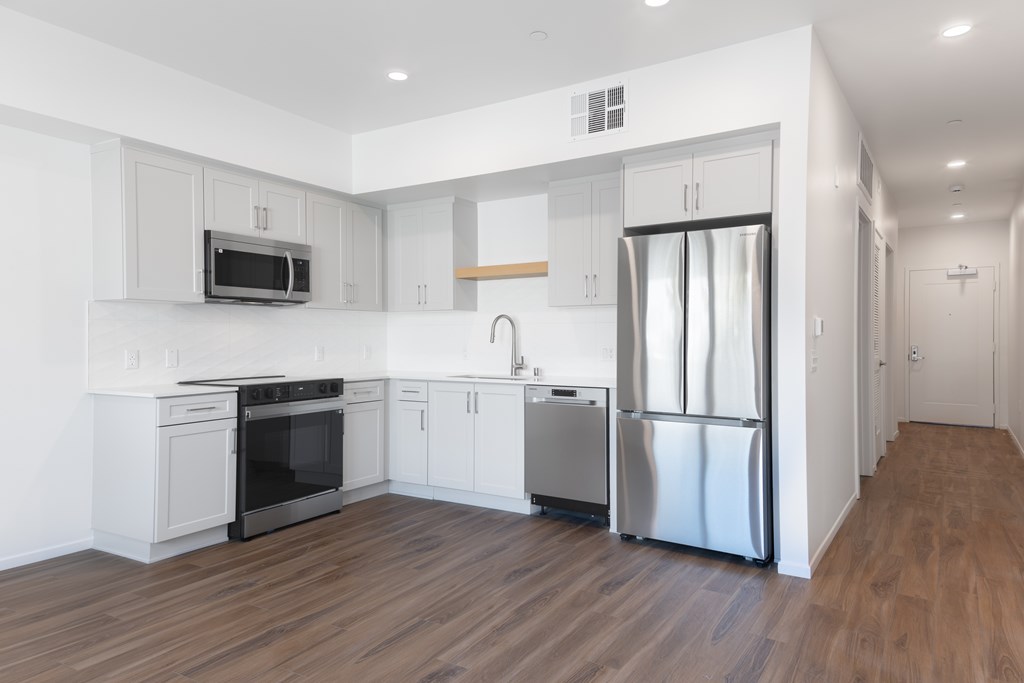 A modern kitchen with stainless steel appliances and wooden floors.