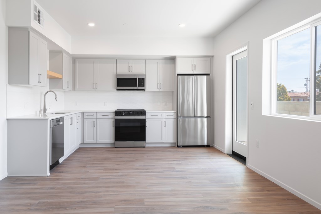 A modern kitchen with stainless steel appliances and wooden floors.