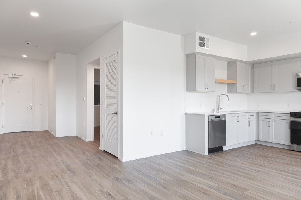 A kitchen with white cabinets and a wooden floor.