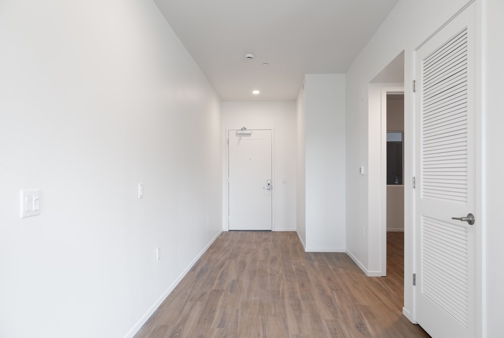 A long white hallway with wood floors and white walls.