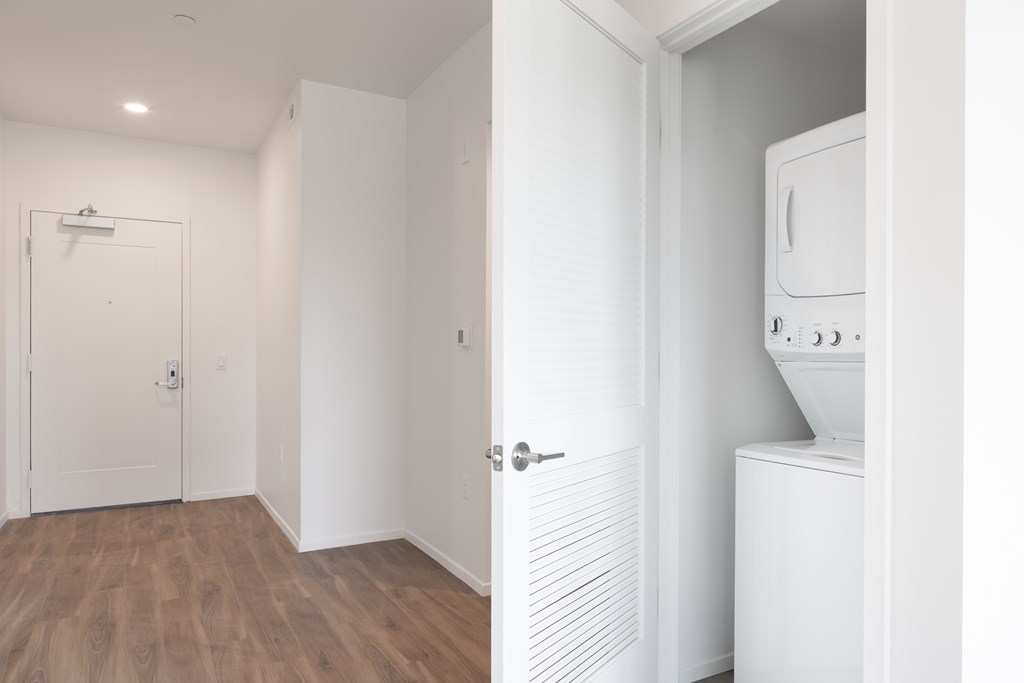 A white door is open to a room with a washing machine.