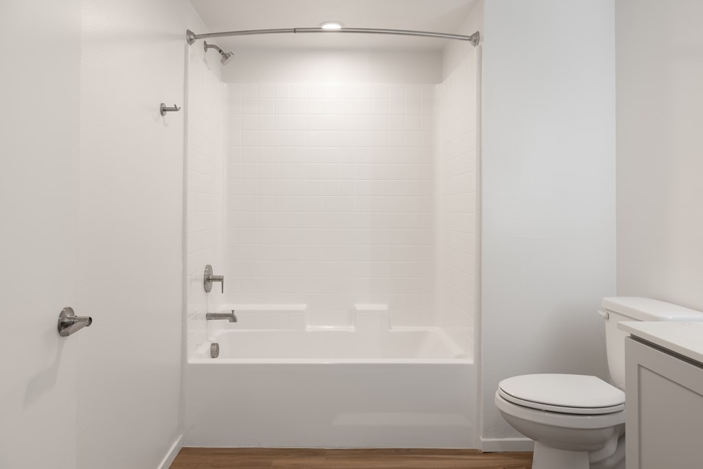 A white bathroom with a toilet, tub, and shower.