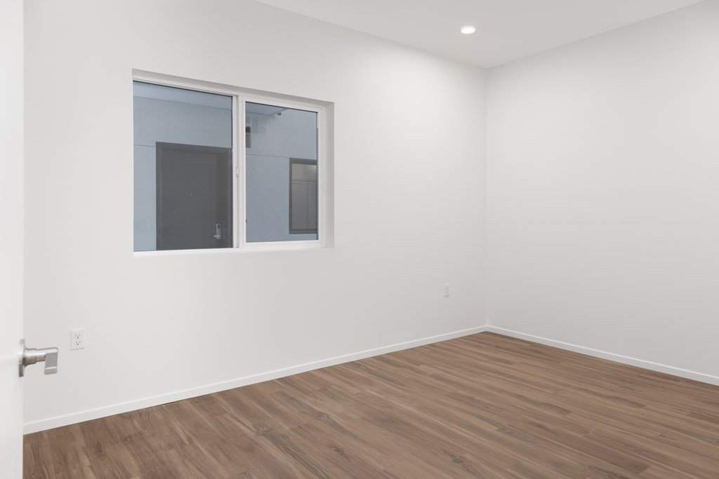 A room with a window and wooden flooring.