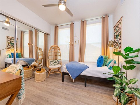 A bedroom with a bed, chair, and potted plant.