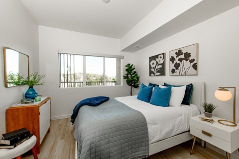 A bedroom with a bed, nightstand, and a window with blinds.