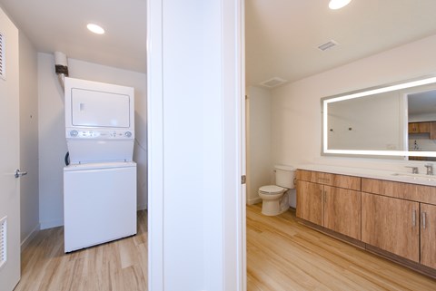 A white refrigerator is in a kitchen next to a toilet.