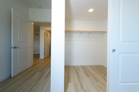 A white door is open to a hallway with a white wall and a white closet with a white door.