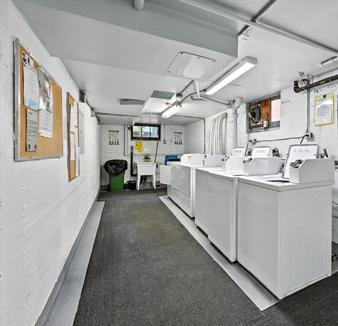 A white room with a long counter and a trash can.