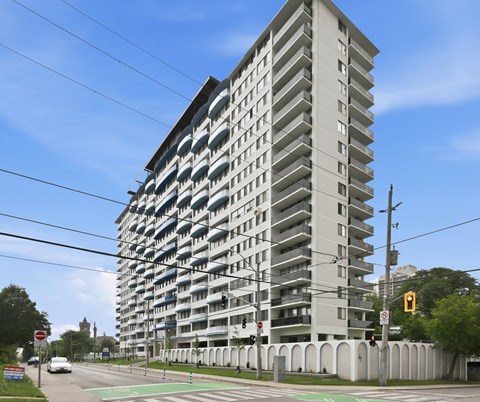 A tall residential building with a grey facade and balconies on each floor.