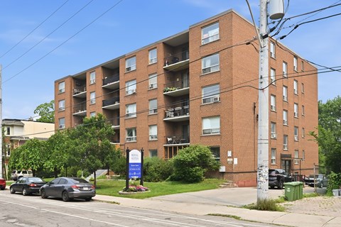 A large brick apartment building with a blue sign in front.