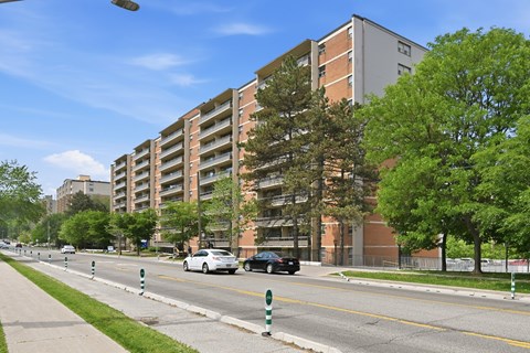 A street with cars and apartment buildings on the side.